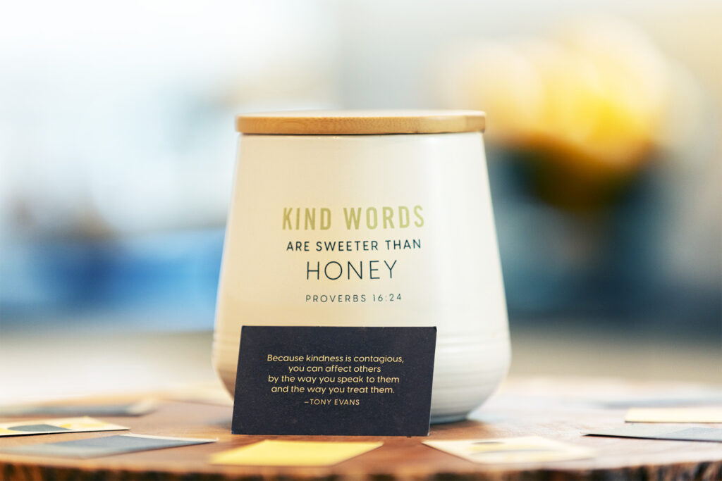 Kind Words are Sweeter Than Honey white jar with lid on table with encouraging kindness cards.