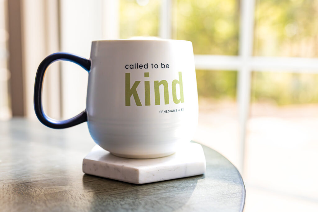 Called to be Kind white mug with black handle on a table.