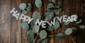 Happy New Year banner resting on top of green leaves on floor.