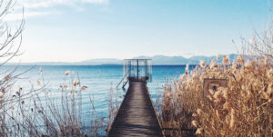 A dock stretching out over a lake with mountains in the background