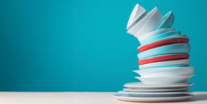 Picture of dishes stacked up high and leaning to the left.