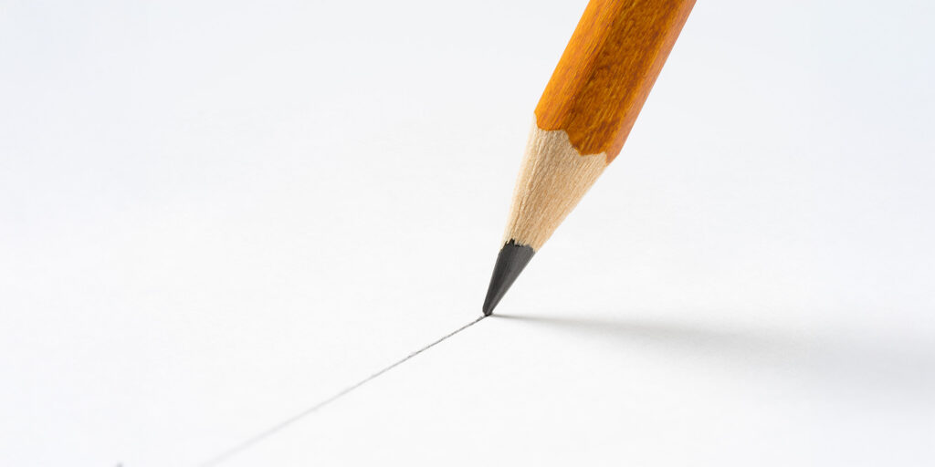 Pencil drawing straight line on white paper.