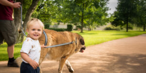 Man and little boy walking a dog on a path.