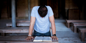 Man leaning over an open Bible on a table.
