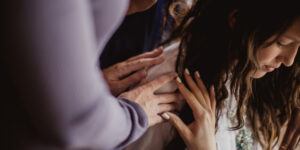 A group of women praying over a kneeling woman
