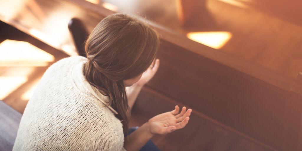 Woman praying in church pew with open hands