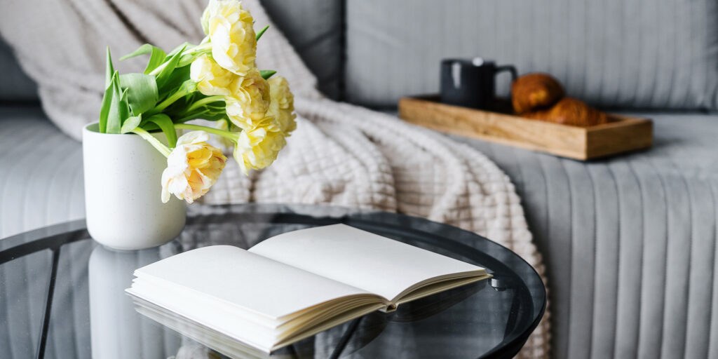 Open book and vase of yellow flowers on side table next to couch